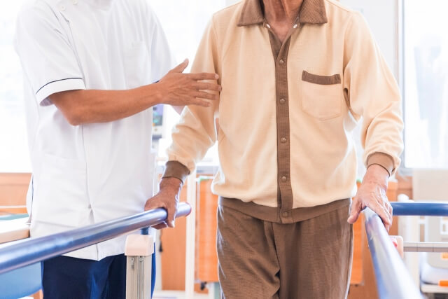 高齢者の歩行介助をする病院で働く理学療法士