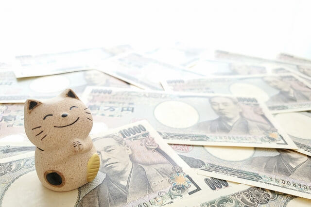 ばらまいた一万円札と笑顔の招き猫