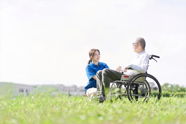 芝生で会話をする高齢者と理学療法士