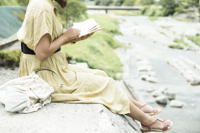 河原で本を読む女性