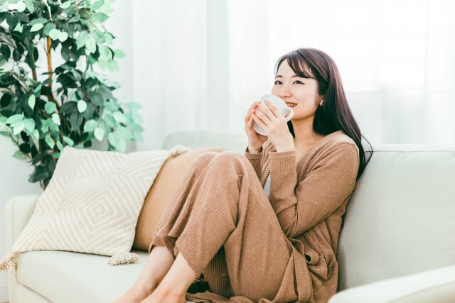 ソファーに座ってコーヒーを飲む女性の写真