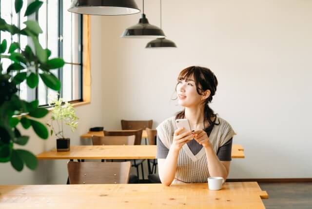 穏やかにカフェでコーヒーを飲む女性の写真