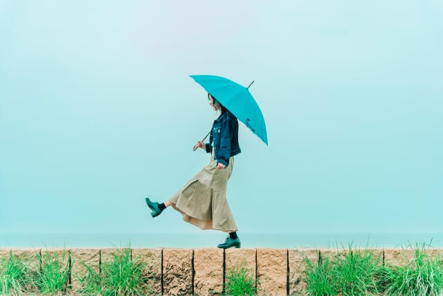 雨の中を傘をさして歩く女性の写真
