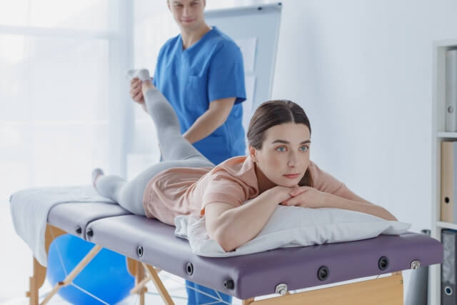 ベッドでリハビリを受ける女性と理学療法士