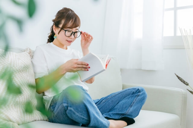 家のソファで読書するおしゃれな日本人女性