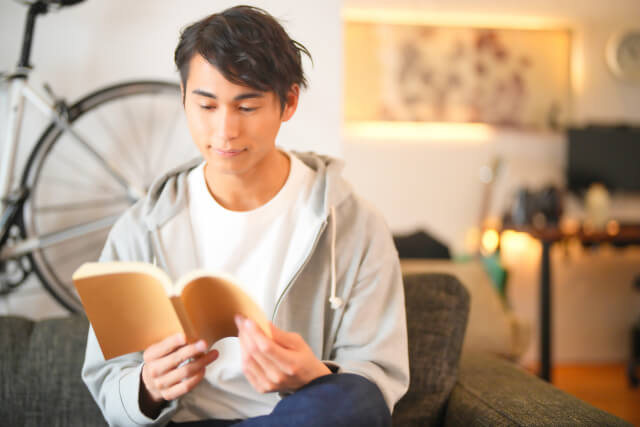 ソファーで読書する４０代独身男性