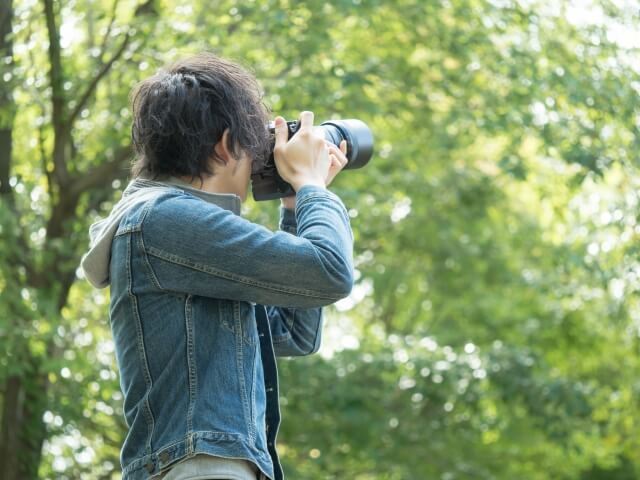 自然の中でカメラを持つ40代独身男性