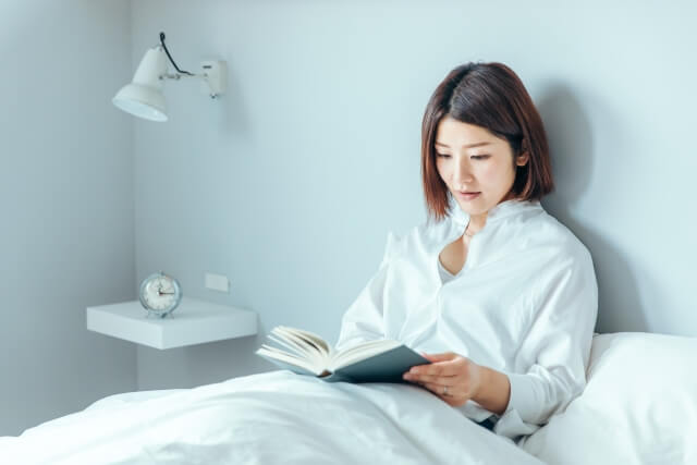 ベッドで本を読む女性