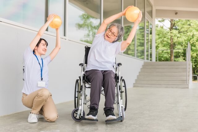 ボール体操する高齢者女性と理学療法士