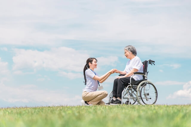 公園を散歩する理学療法士と車椅子の高齢者女性