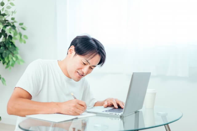 家でパソコンを使って勉強する男性