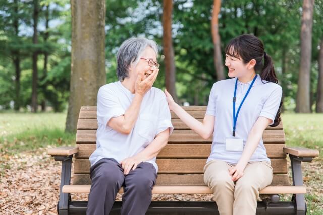 公園で話す高齢者と笑顔の理学療法士
