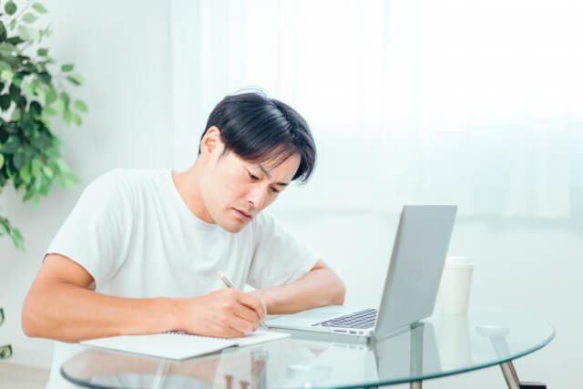 家でパソコンを使って勉強する男性