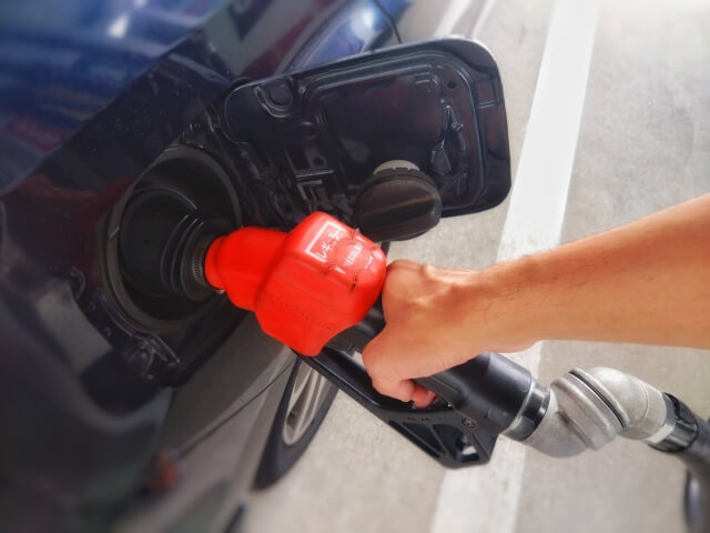 ガソリンスタンドで車に給油している男性