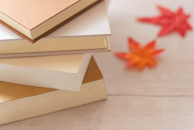 白い木目調のテーブルにある本と紅葉