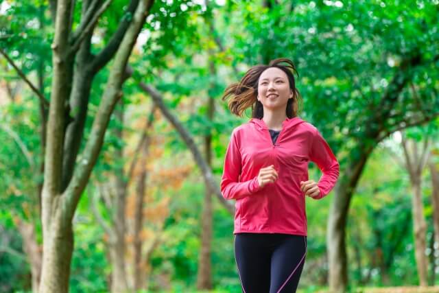 緑の中でジョギングをする若い女性
