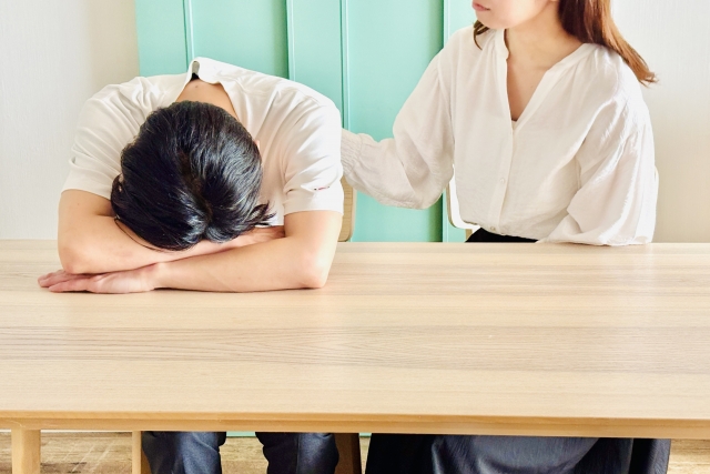 家のリビングで悩む男性を励ます女性