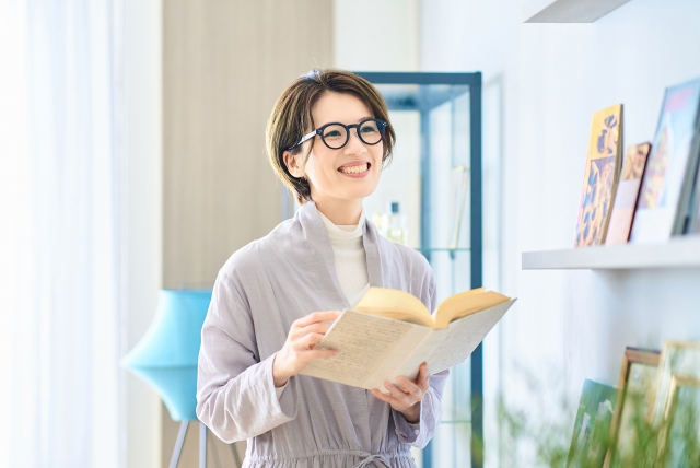 部屋で読書する40代女性