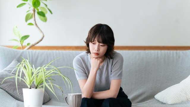 リビングのソファに座って考える女性