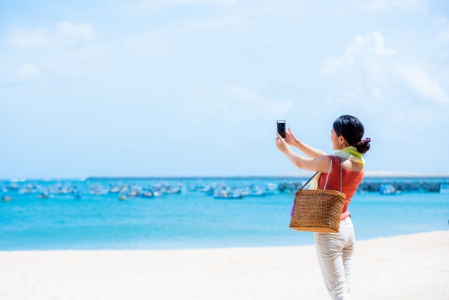 スマホで海の写真を撮る女性