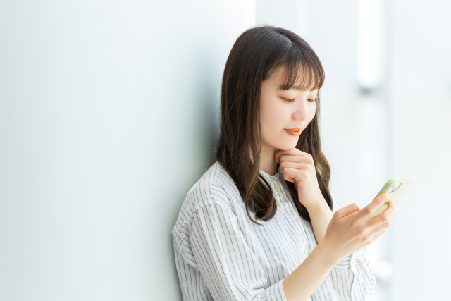 微笑みながらスマートフォンを使う若い女性