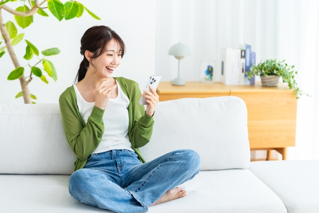 部屋でスマホを操作する若い女性